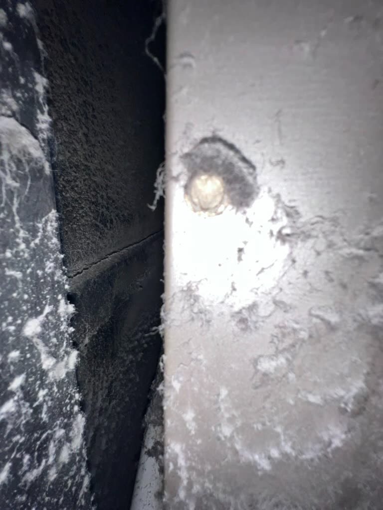 Mold staining on duct board insulation with visible fiberglass debris near HVAC plenum connection