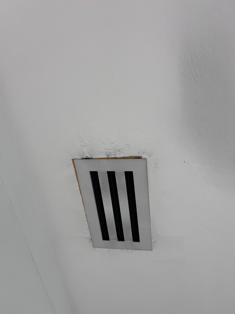 Close-up of discolored ceiling drywall surrounding air conditioning supply vent