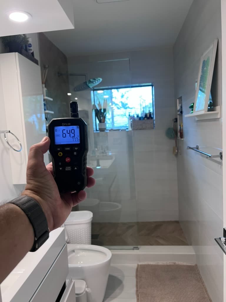 Thermo-hygrometer reading 64.9 degrees and 77.7 percent relative humidity in primary bathroom