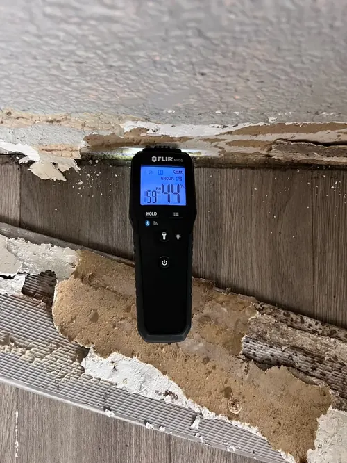 Moisture meter reading elevated humidity behind a water-damaged ceiling trim in Parkland, FL