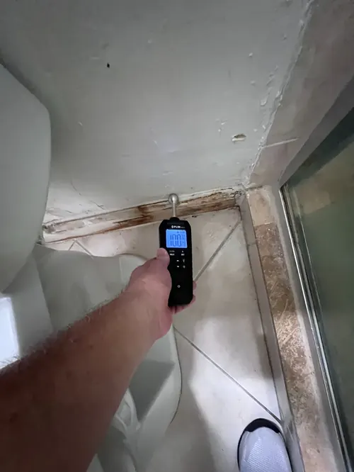 Pin-type moisture meter verifying water intrusion near a shower window frame in Weston, FL