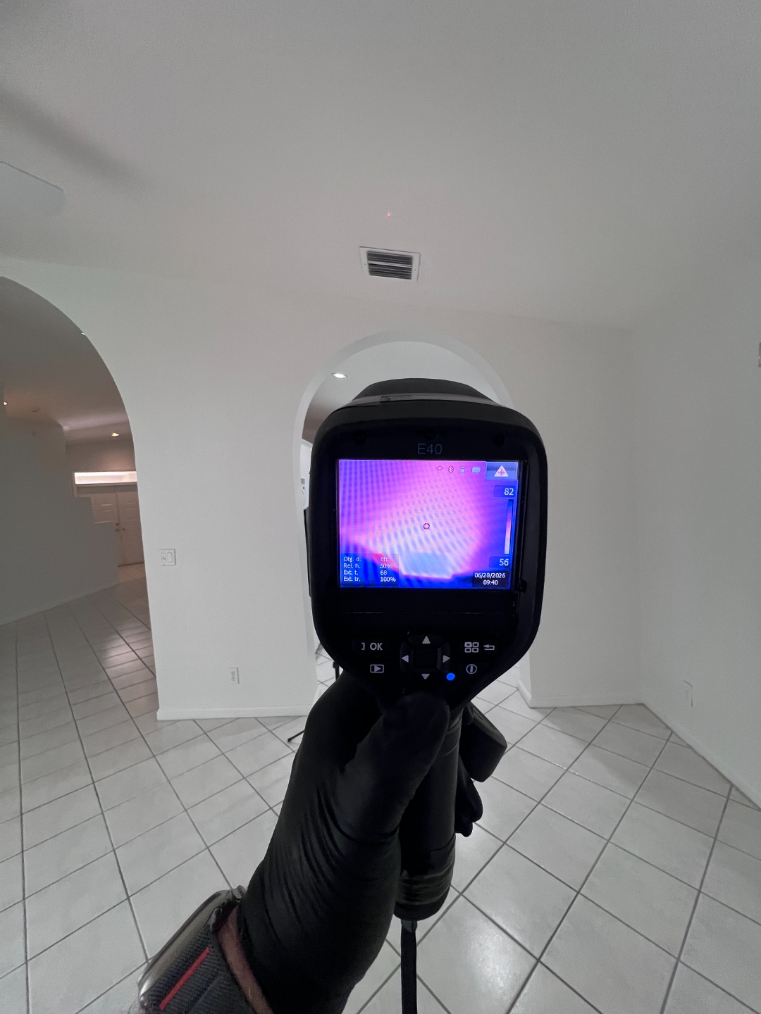 FLIR thermal imaging camera displaying a ceiling temperature scan near a supply vent in the home's main living area, with a reading of 82 degrees Fahrenheit